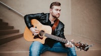 a man sitting on steps with an acoustic guitar
