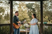 a bride and groom standing in front of a gazebo with an acoustic guitar