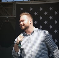 a man holding a microphone in front of an american flag